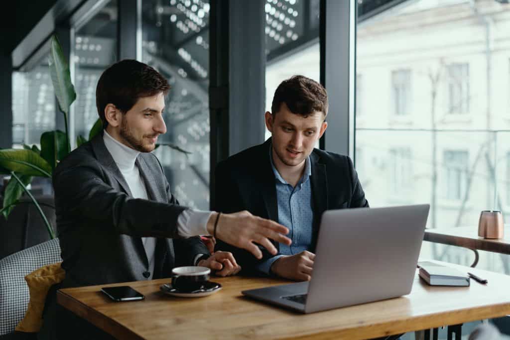 Two Businessmen Pointing Laptop Screen While Discussing