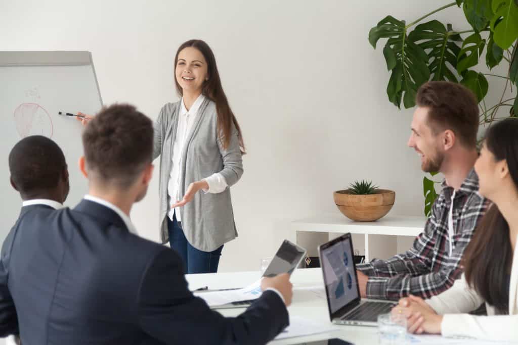 Smiling Young Employee Giving Presentation Working With Flipchar